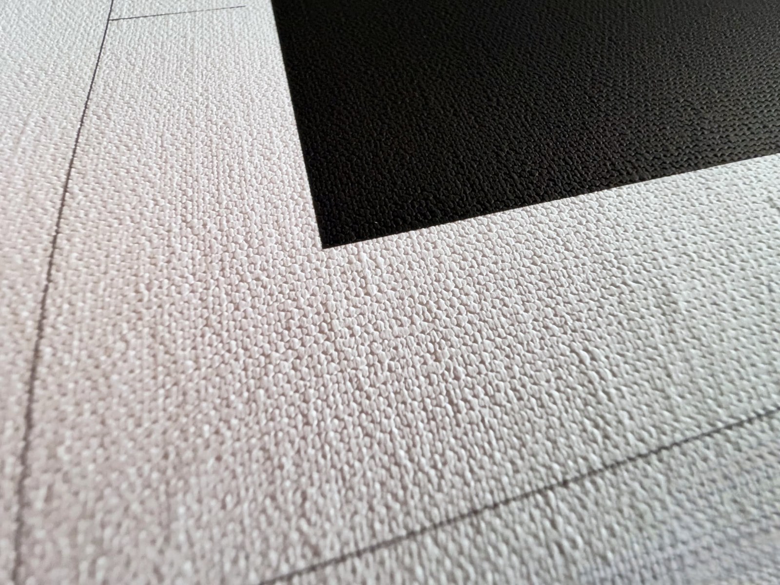 Up-close view of uncoated Chromata White canvas weave beside a deep black printed block